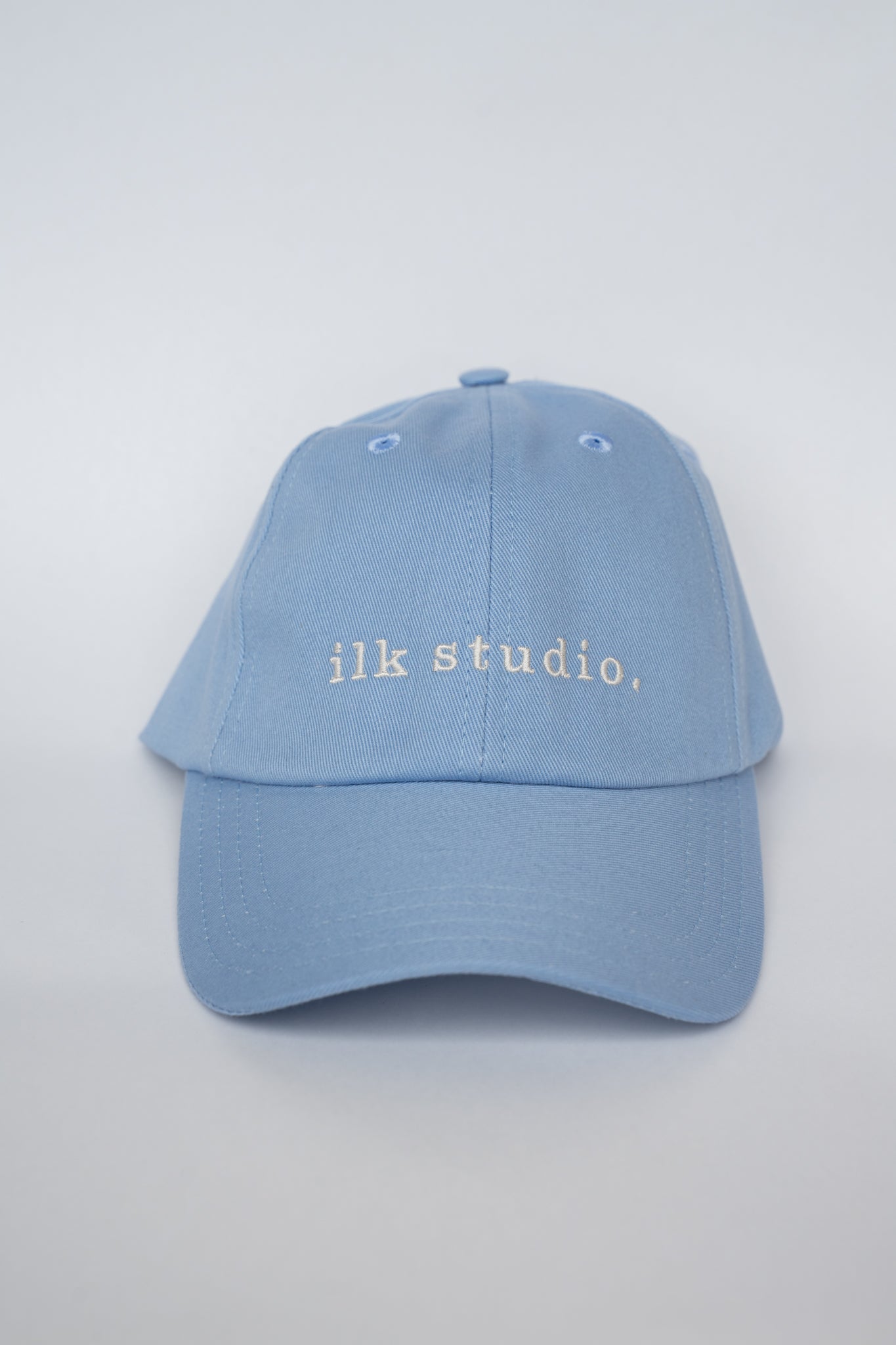 Light blue cap with 'ilk studio.' text on a light gray background